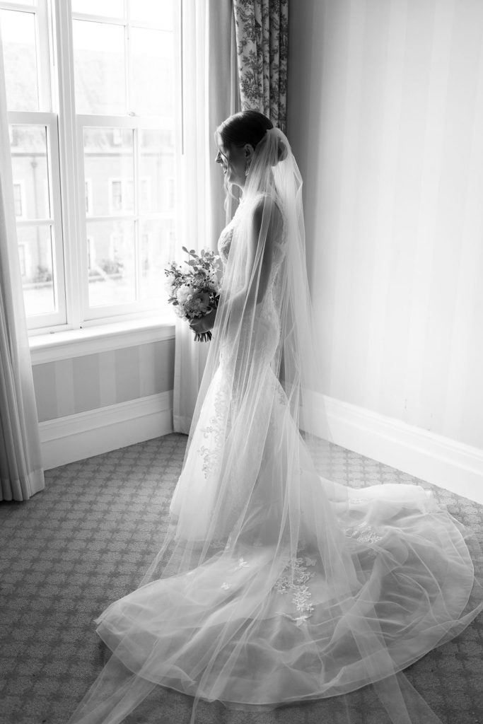bride looking out the window at royal park hotel on her wedding day in rochester michigan